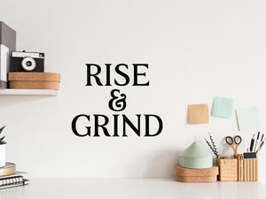 Wall decal for the office that says ‘Rise And Grind’ in a print font on an office wall.