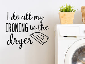 Laundry room wall decal that says ‘I Do All My Ironing In The Dryer’ in a script font on a laundry room wall.