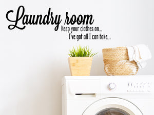 Laundry room wall decal that says ‘Laundry Room Keep Your Clothes On I've Got All I Can Take’ in a cursive font on a laundry room wall.