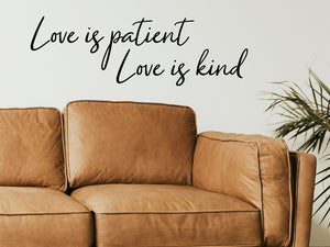Living room wall decals that say ‘Love Is Patient Love Is Kind’ in a cursive font on a living room wall. 