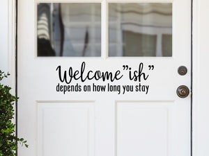 Front door decal that says, ‘Welcomeish Depends On How Long You Stay’ in a print font on a front porch door. 