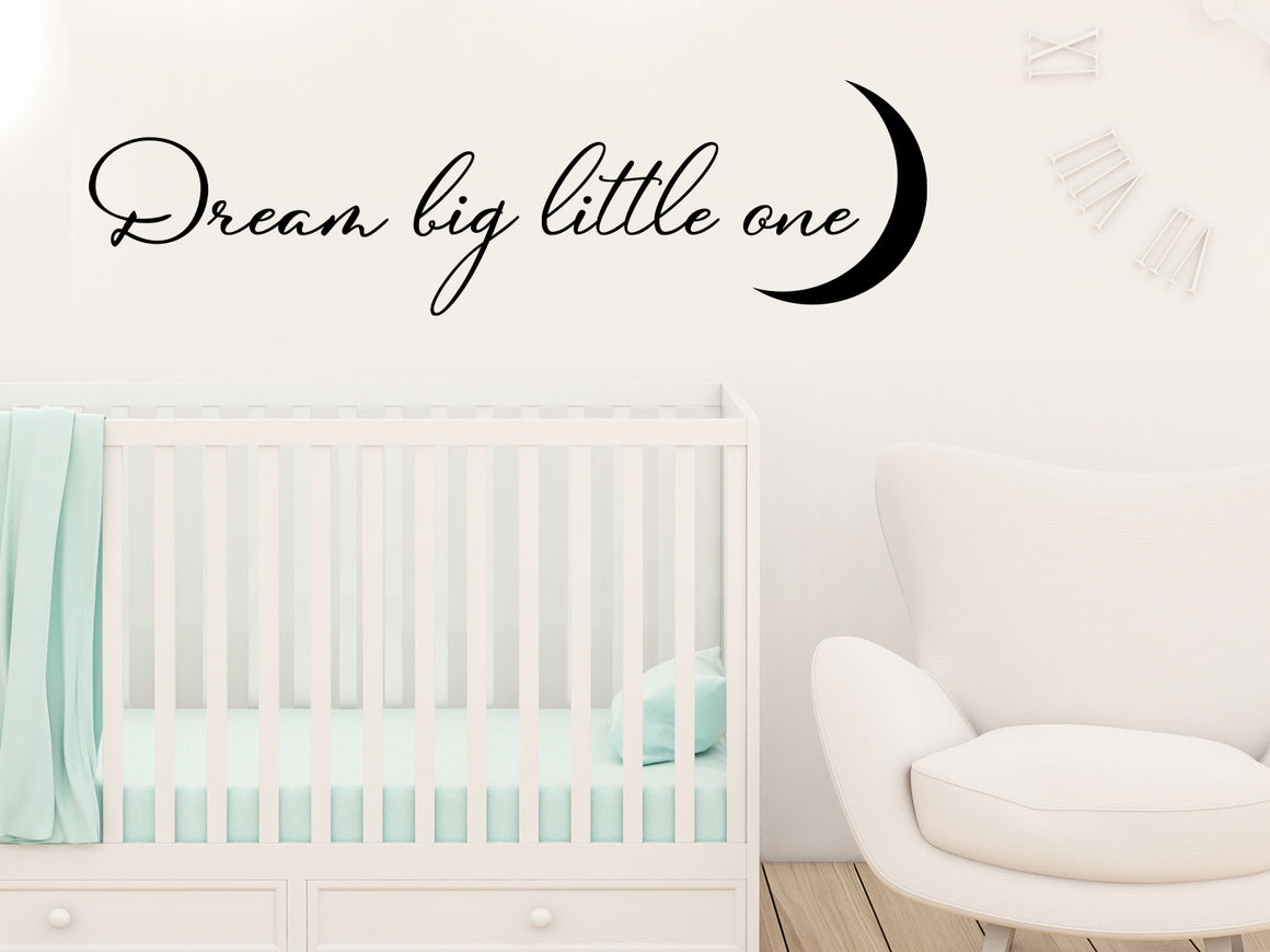 Wall decal for kids that says ‘Dream Big Little One’ in a cursive font on a kid’s room wall. 