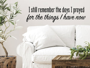 Living room wall decals that say ‘I Still Remember The Days I Prayed For The Things I Have Now’ in a script font on a living room wall. 