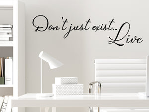 Wall decal for the office that says ‘Don't Just Exist Live’ in a cursive font on an office wall.