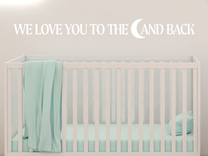 Wall decal for kids in a white color that says ‘We Love You To The Moon And Back’ in a bold font on a kid’s room wall. 
