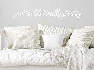 Wall decal for kids in a white color that says ‘You're Like Really Pretty’ in a cursive font on a kid’s room wall. 