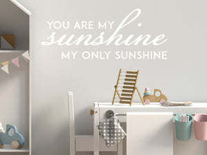 Wall decal for kids in a white color that says ‘You Are My Sunshine’ in a script font on a kid’s room wall. 