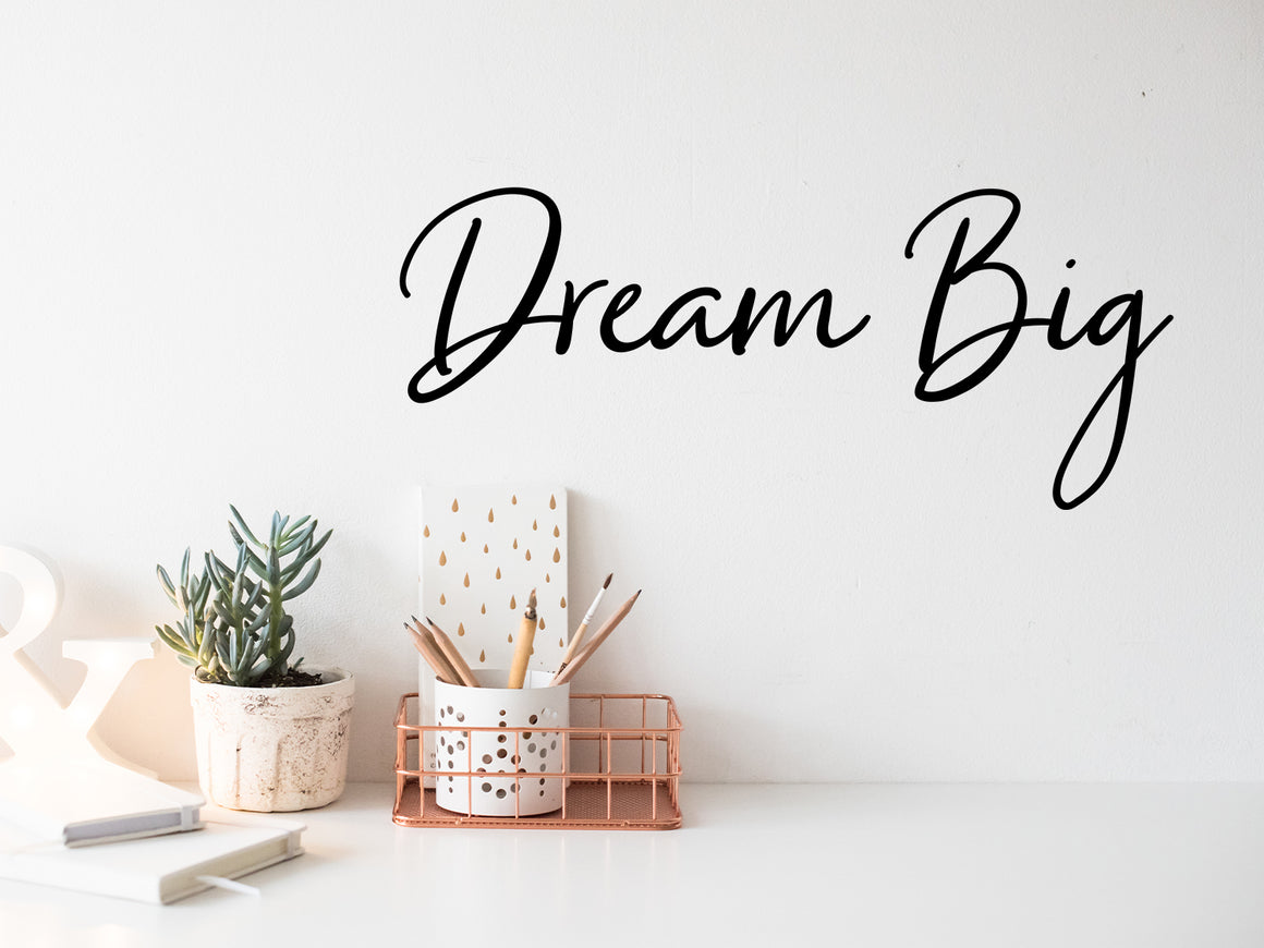 Wall decal for the office that says ‘Dream Big’ in a cursive font on an office wall.