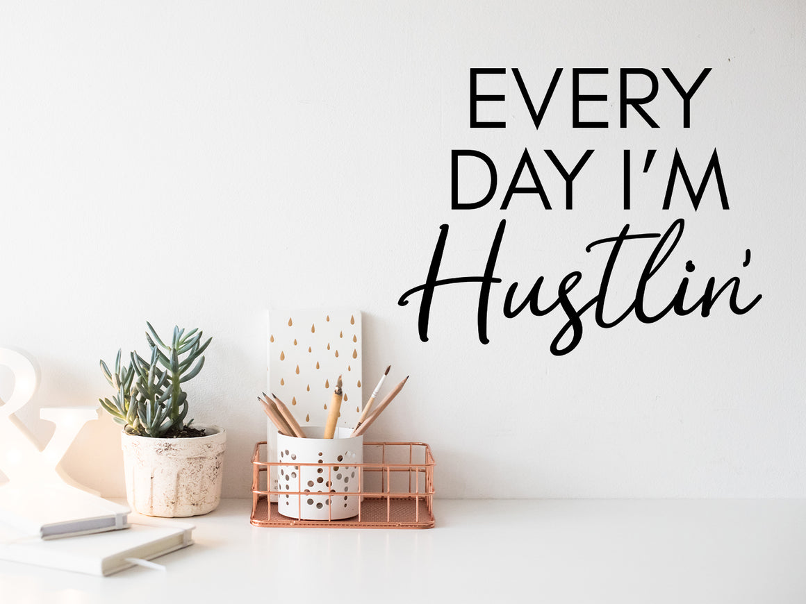 Wall decal for the office that says ‘Every Day I'm Hustlin'’ in a script font on an office wall.