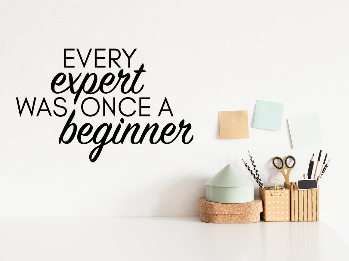 Wall decal for the office that says ‘Every Expert Was Once A Beginner’ in a script font on an office wall.